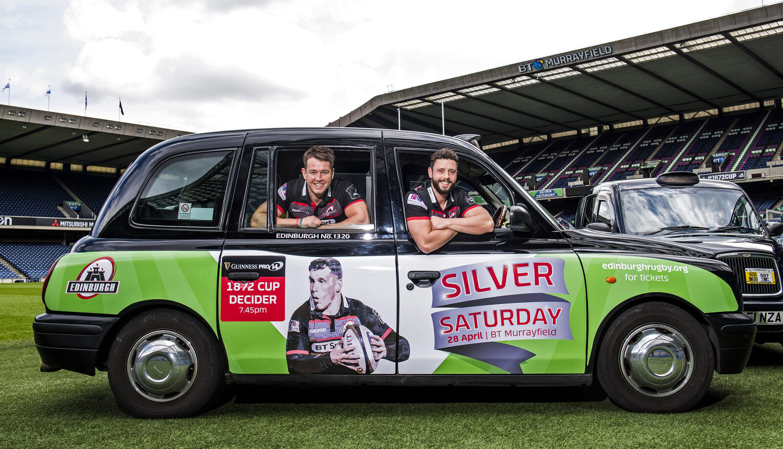 Two Edinburgh Rugby players leaning out of a branded taxi promoting Silver Saturday at BT Murrayfield